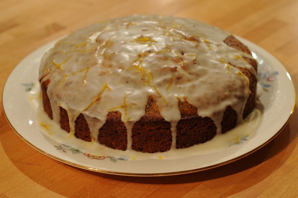 Easy lemon cake with glaze drizzle on a white plate.